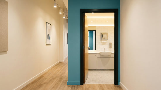 UK office washroom transition — supplier audit checklist on clipboard, paper rolls and dispensers ready for switchover