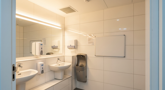 Inspection-ready UK commercial washroom with compliance signage and proper hand wash station
