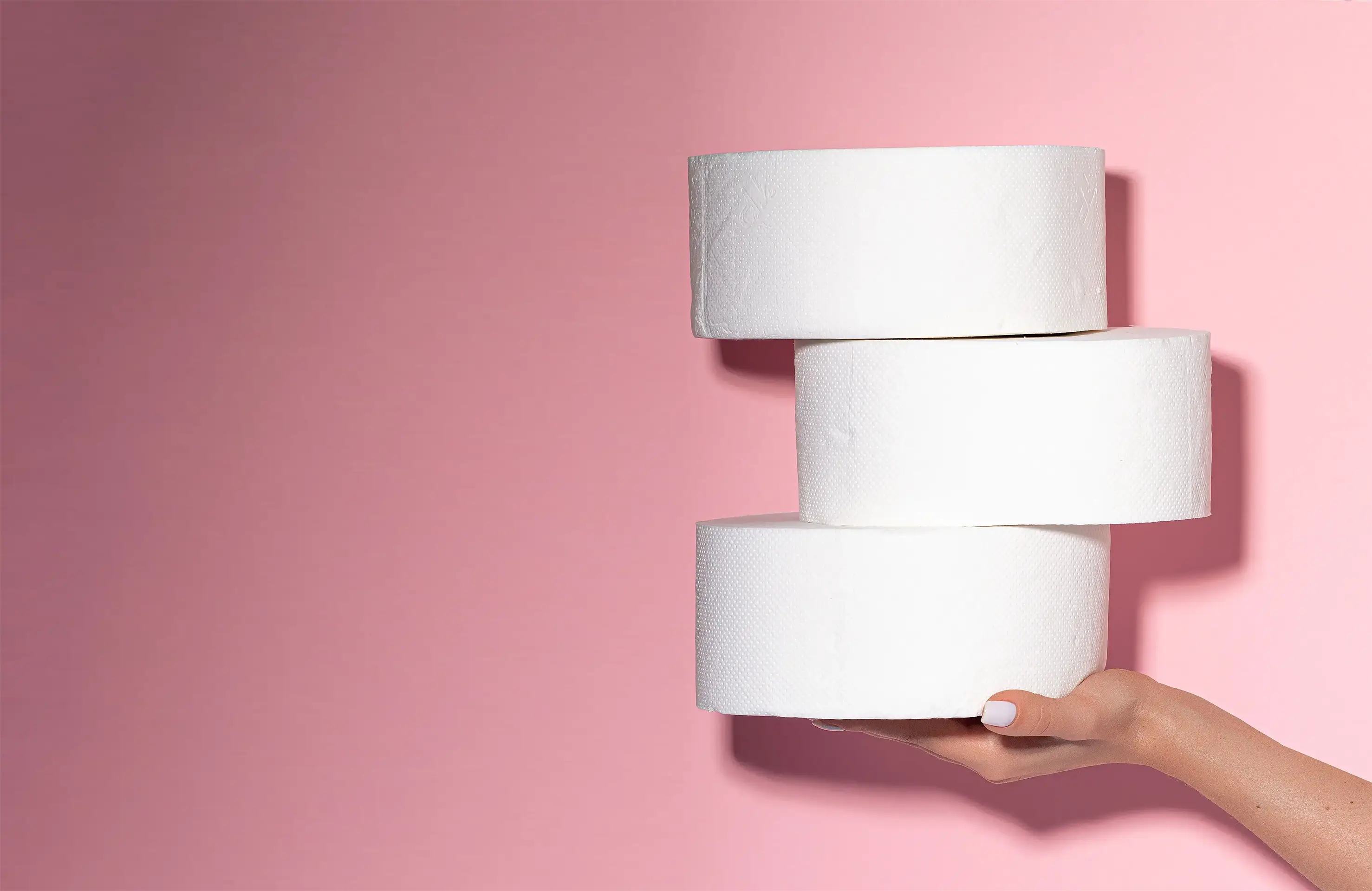 Three white cylindrical objects held by a hand against a pink background