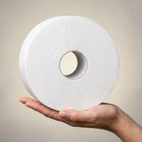 Compact jumbo toilet paper roll held in hand for scale — 21 cm diameter, wider than an adult palm. Commercial-format roll, not domestic size.