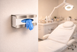 Wall-mounted stainless steel glove dispenser with blue disposable gloves in a beauty clinic